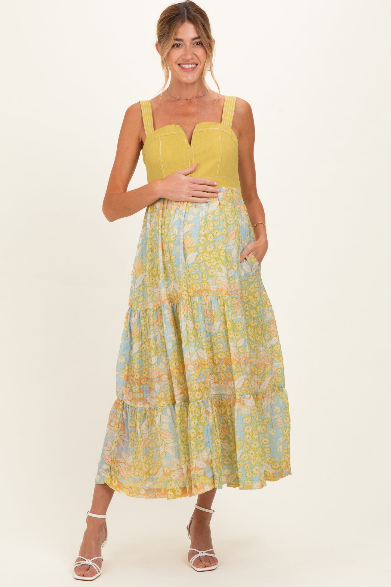 woman wearing a yellow and blue floral maternity maxi dress with a baby bump and pockets
