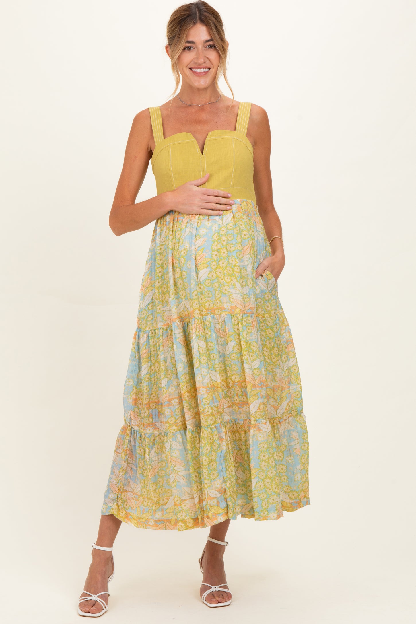 woman wearing a yellow and blue floral maternity maxi dress with a baby bump and pockets