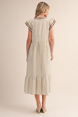 woman wearing a cream and brown striped maxi dress with ruffle sleeves and a tiered hem, shown from the back