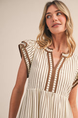 woman wearing a striped cream and brown short sleeve dress with a v-neck and pleated detailing