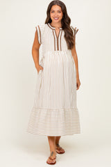 woman wearing a striped maternity dress with short sleeves and a tiered hem, posing with hands in pockets