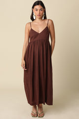 woman wearing a brown sleeveless maxi dress with a v-neckline and gathered waist, styled with green sandals