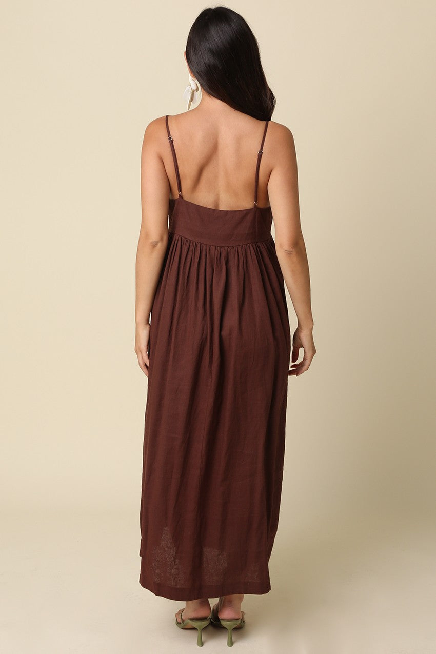 woman wearing a brown backless maxi dress with a flowy silhouette and adjustable straps
