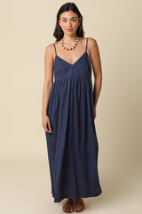 woman wearing a navy blue spaghetti strap maxi dress with a cinched waist and a relaxed fit