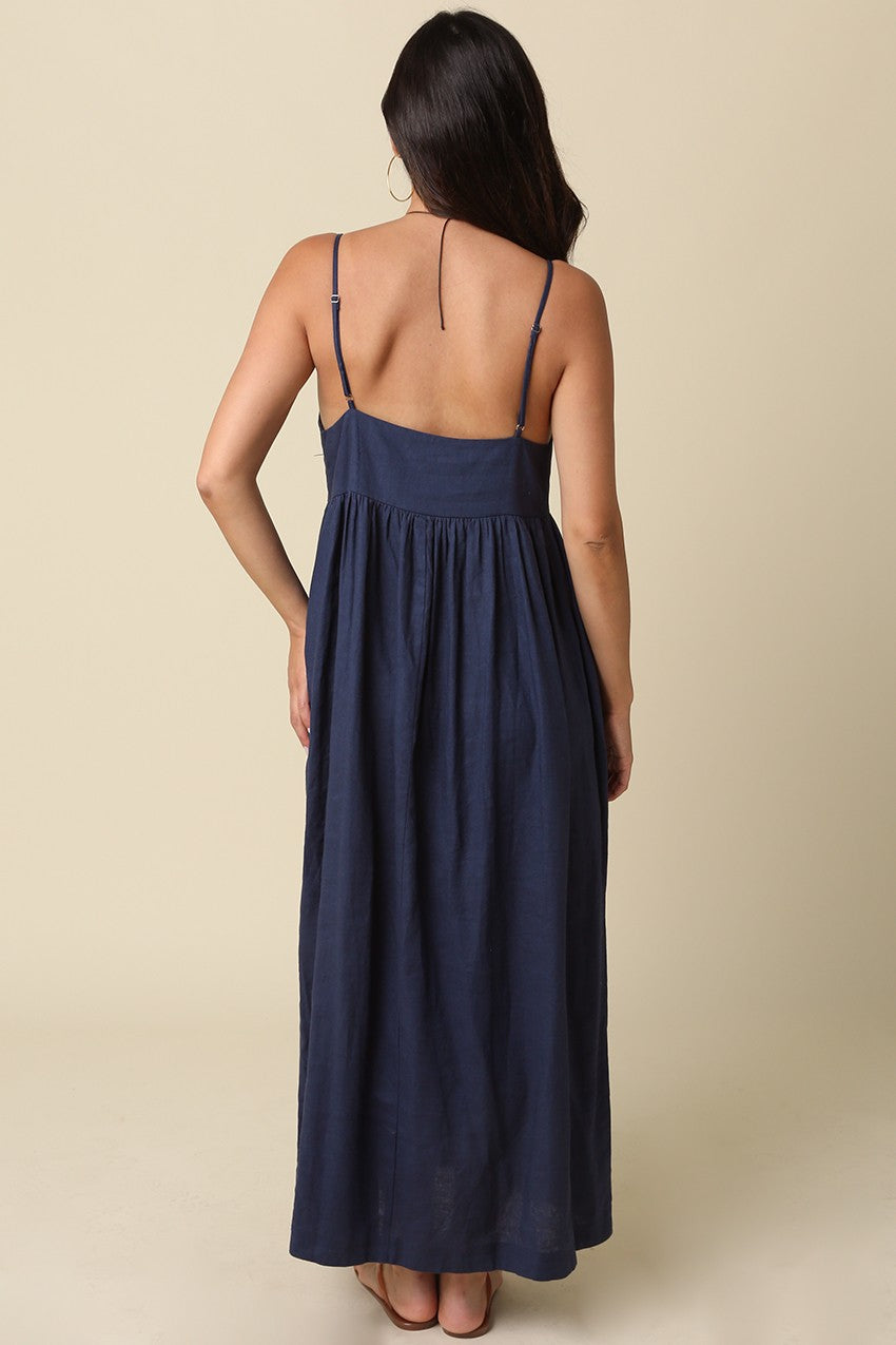 woman wearing a navy blue maxi dress with spaghetti straps and a flowy back design