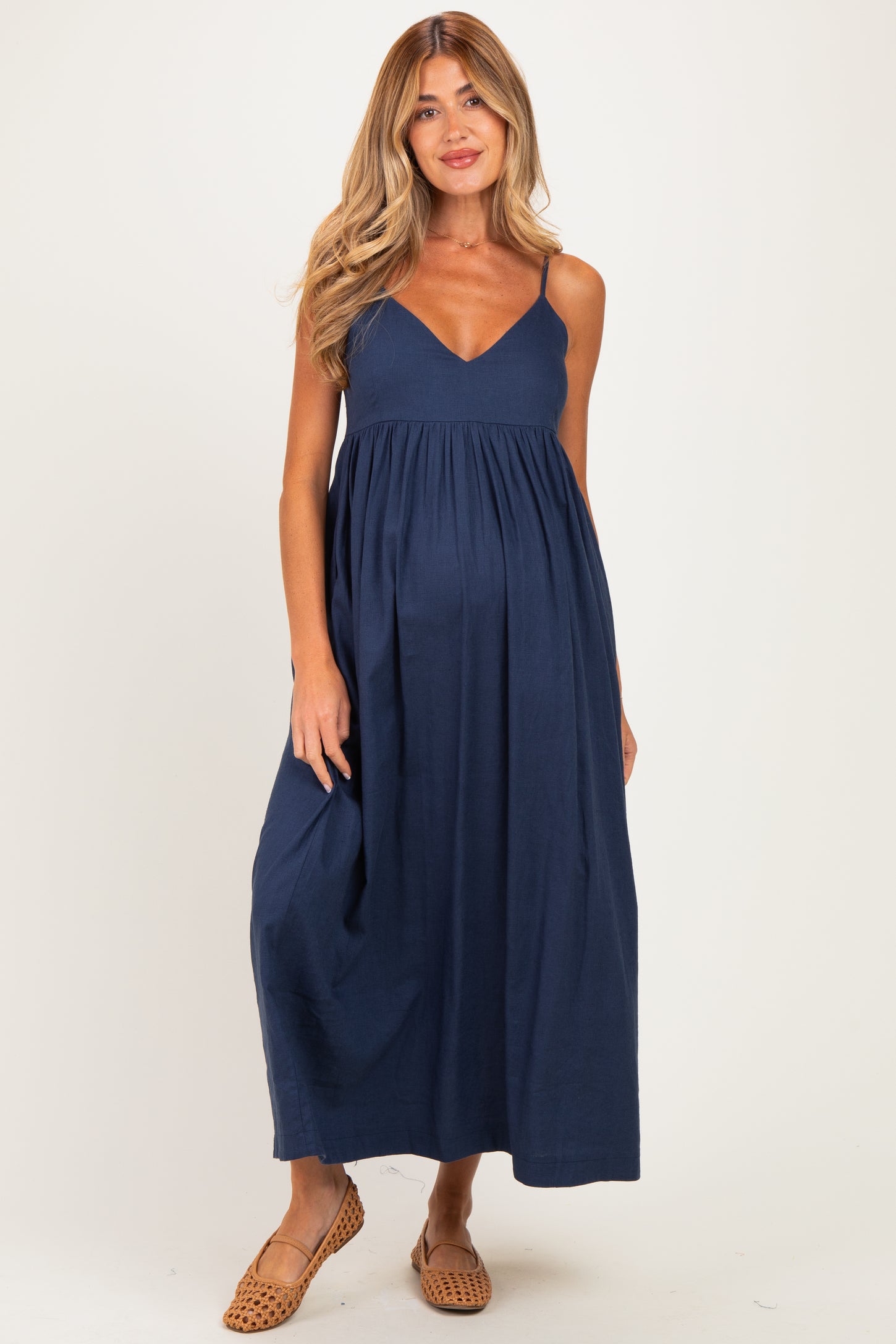 woman wearing a navy blue maternity maxi dress with a v-neckline and a baby bump visible