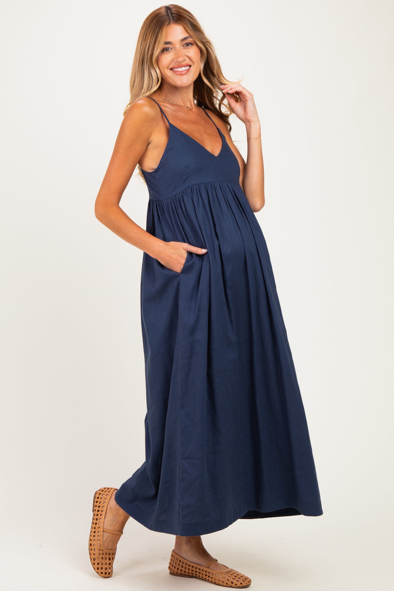 woman wearing a navy blue maternity maxi dress with a v-neck and pockets, showcasing her baby bump