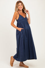 woman wearing a navy blue maternity maxi dress with a v-neck and pockets, showcasing her baby bump