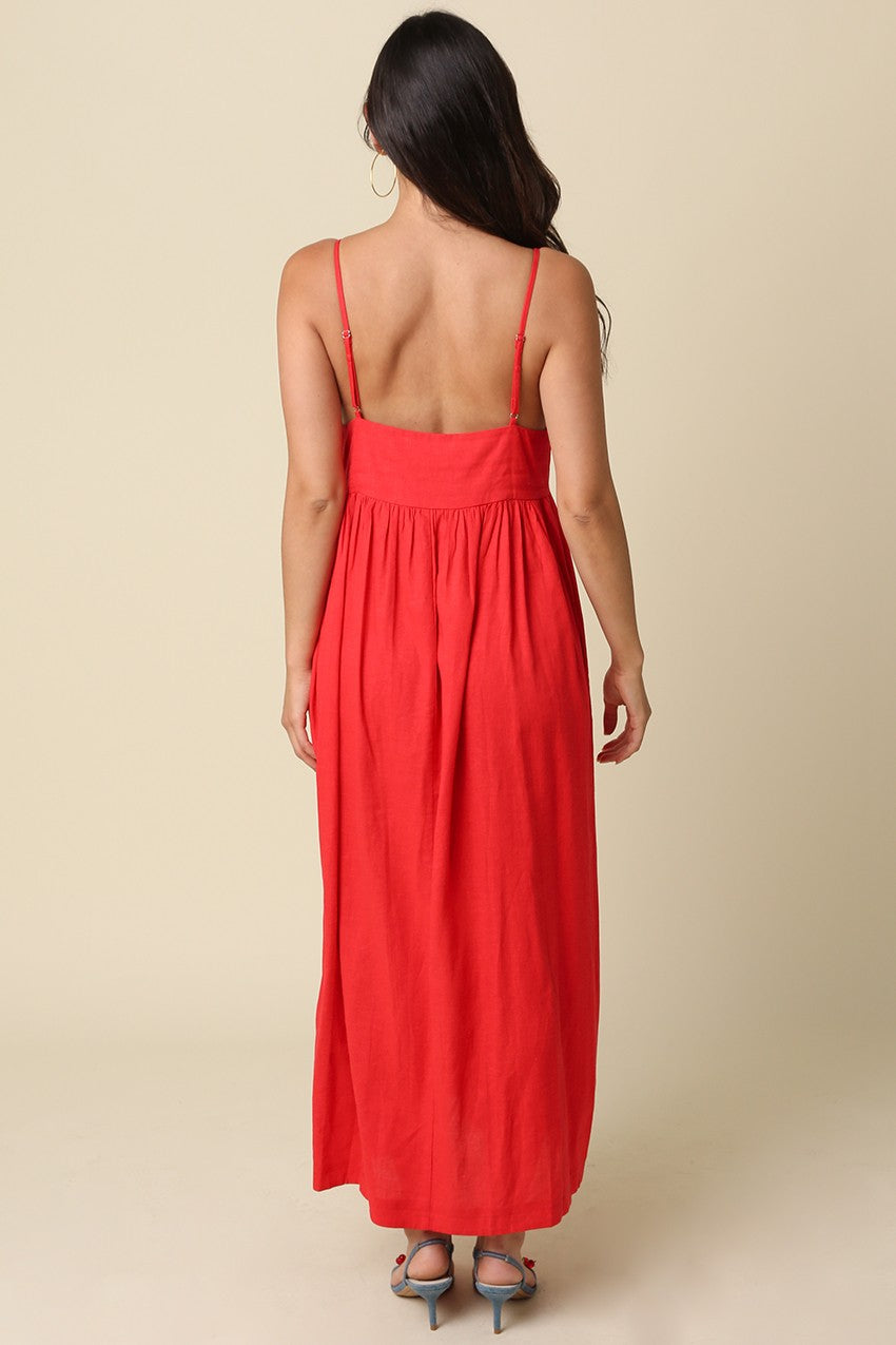 woman wearing a back-view of a red maxi dress with thin straps and a gathered waistline