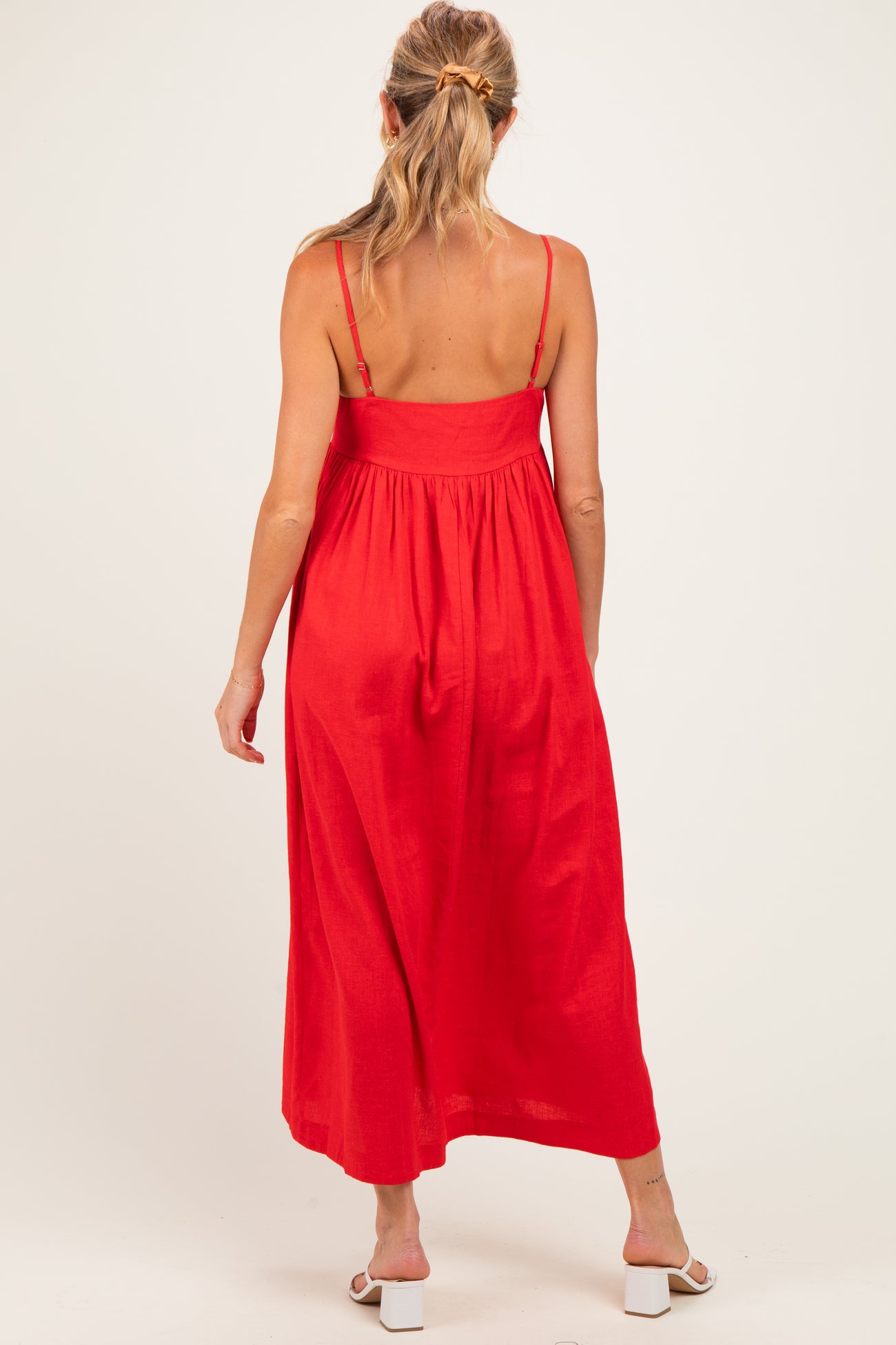 woman wearing a red maternity maxi dress with adjustable straps and a relaxed fit, showing a baby bump from behind