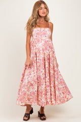 woman wearing a pink and white floral maternity dress with spaghetti straps and a flowy skirt, showing her baby bump