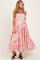 woman wearing a pink and white floral maternity dress with spaghetti straps and a flowy skirt, showing her baby bump