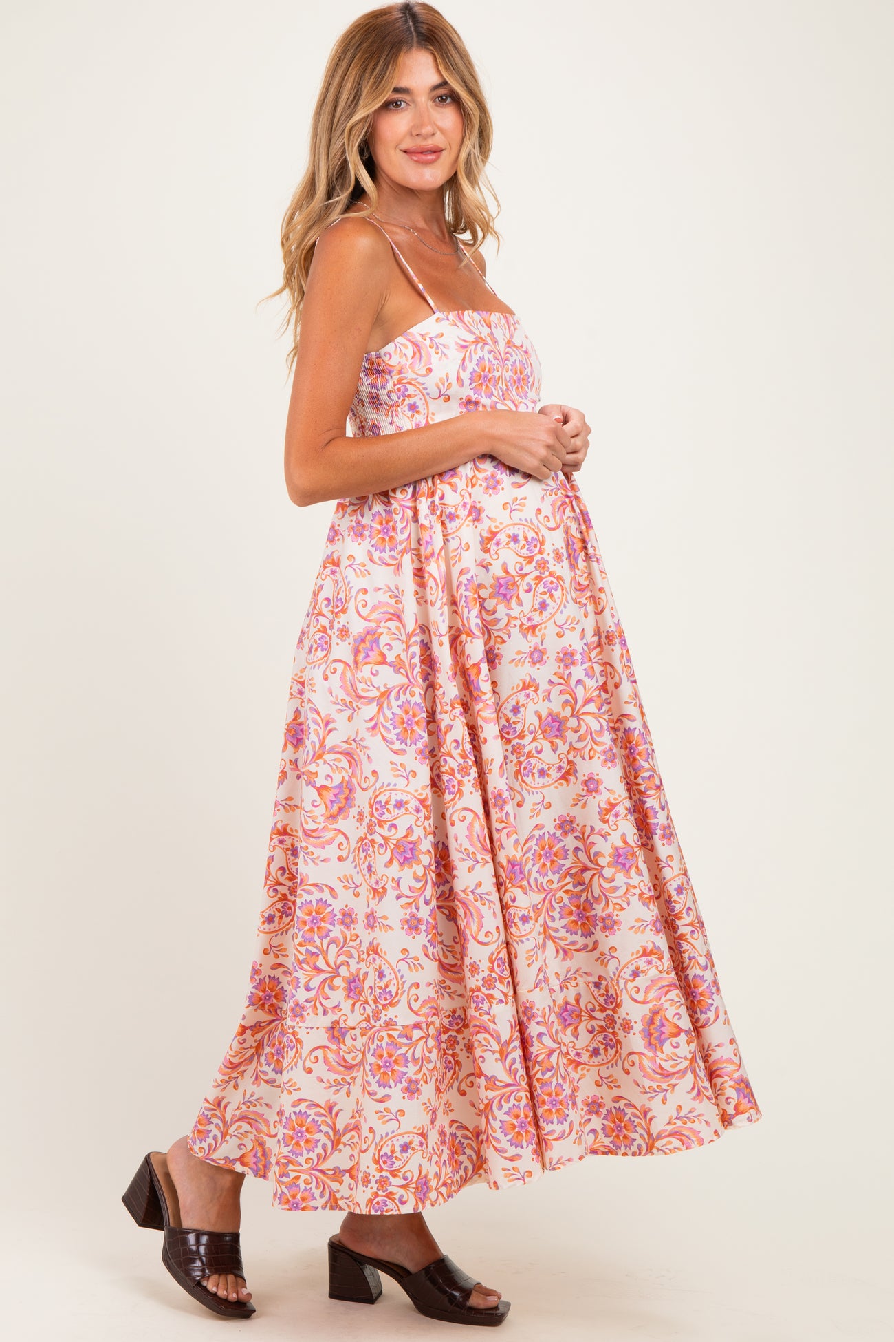 woman wearing a floral print maternity maxi dress with adjustable straps and a visible baby bump