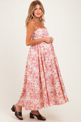woman wearing a floral print maternity maxi dress with adjustable straps and a visible baby bump