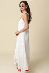 woman wearing a white maxi dress with thin straps and vertical stripes, styled with sunglasses and red heels