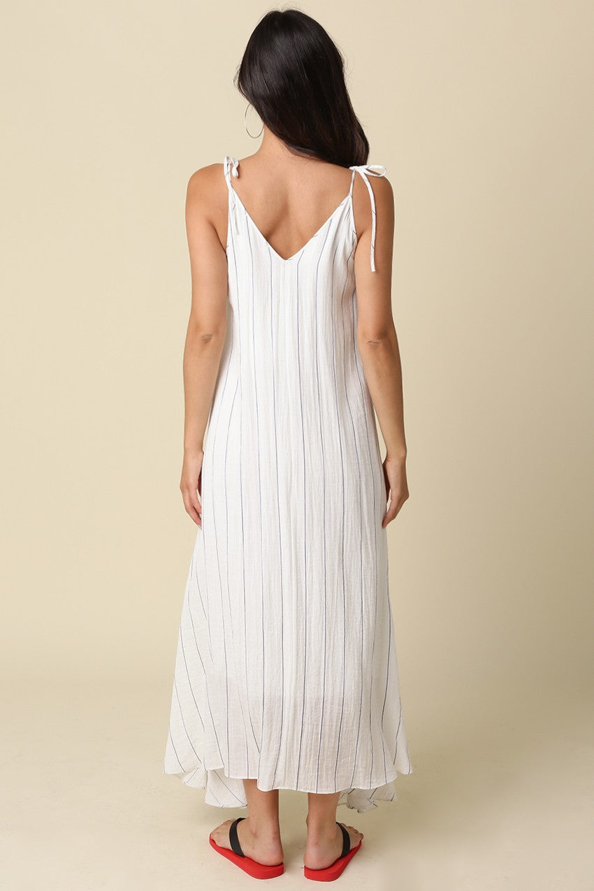 woman wearing a white striped maxi dress with tie straps and a flowing silhouette from the back