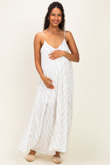 woman wearing a white striped maternity maxi dress and gently holding her baby bump