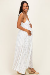 woman wearing a white and navy striped maternity maxi dress, holding her baby bump and smiling