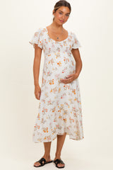 woman wearing a floral maternity dress with short ruffled sleeves and holding her baby bump
