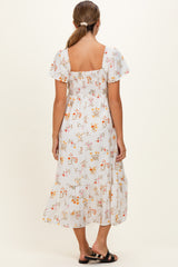 woman wearing a floral maternity dress with short sleeves and a smocked back, view from the back