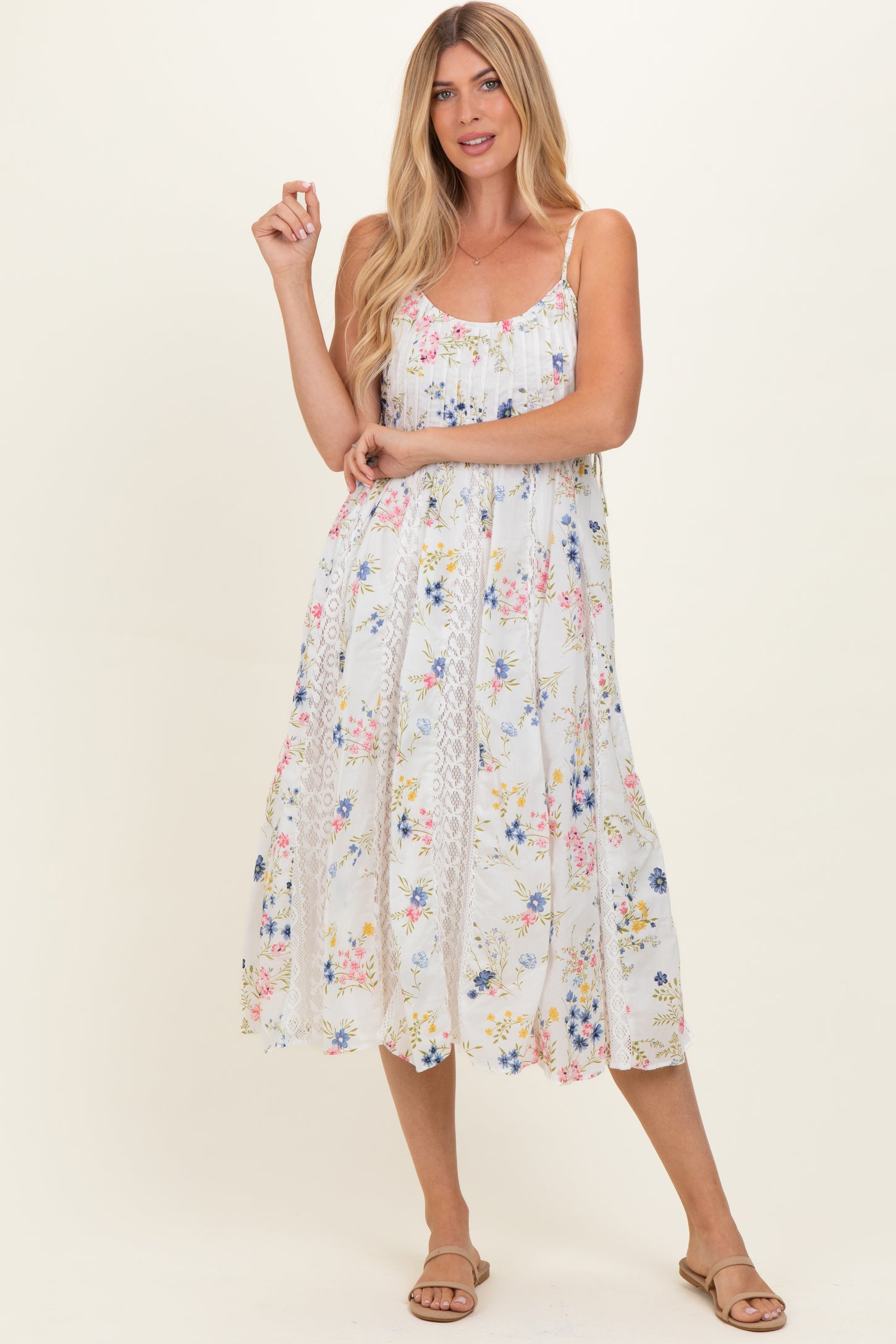 woman wearing a floral midi dress with adjustable spaghetti straps and a flared hem, styled with flat sandals