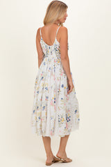 woman wearing a white floral maxi dress with a lace hem and spaghetti straps, viewed from the back