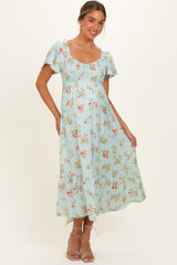 woman wearing a light blue floral maternity dress with short sleeves and a smocked bodice, showcasing her baby bump