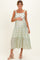 woman wearing a light green floral maternity dress with tie straps and holding her baby bump
