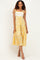 woman wearing a floral yellow and white midi dress with shoulder ties and a tiered design