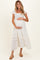 woman wearing a white maternity dress with ruffle sleeves and smocked bodice, holding her baby bump