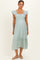 woman wearing a light green maternity dress with ruffle sleeves and a tiered hemline