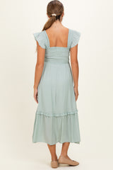 woman wearing a light green maternity dress with ruffled sleeves and a tiered hem, shown from the back