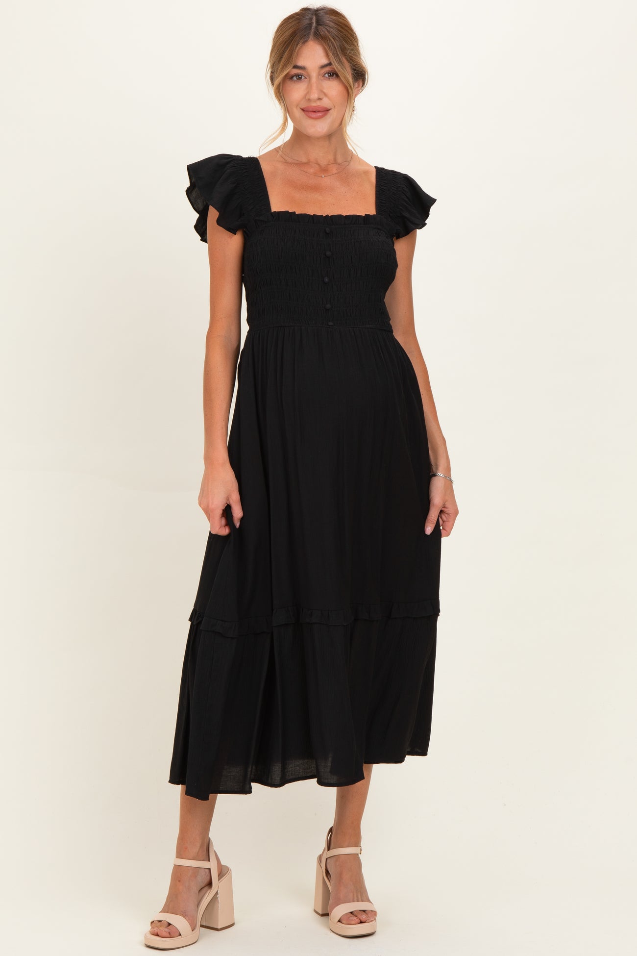 woman wearing a black maternity dress with ruffle sleeves and a tiered skirt