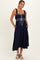 woman wearing a navy blue maternity dress with ruffled straps and a drawstring waist, pockets visible, and a baby bump