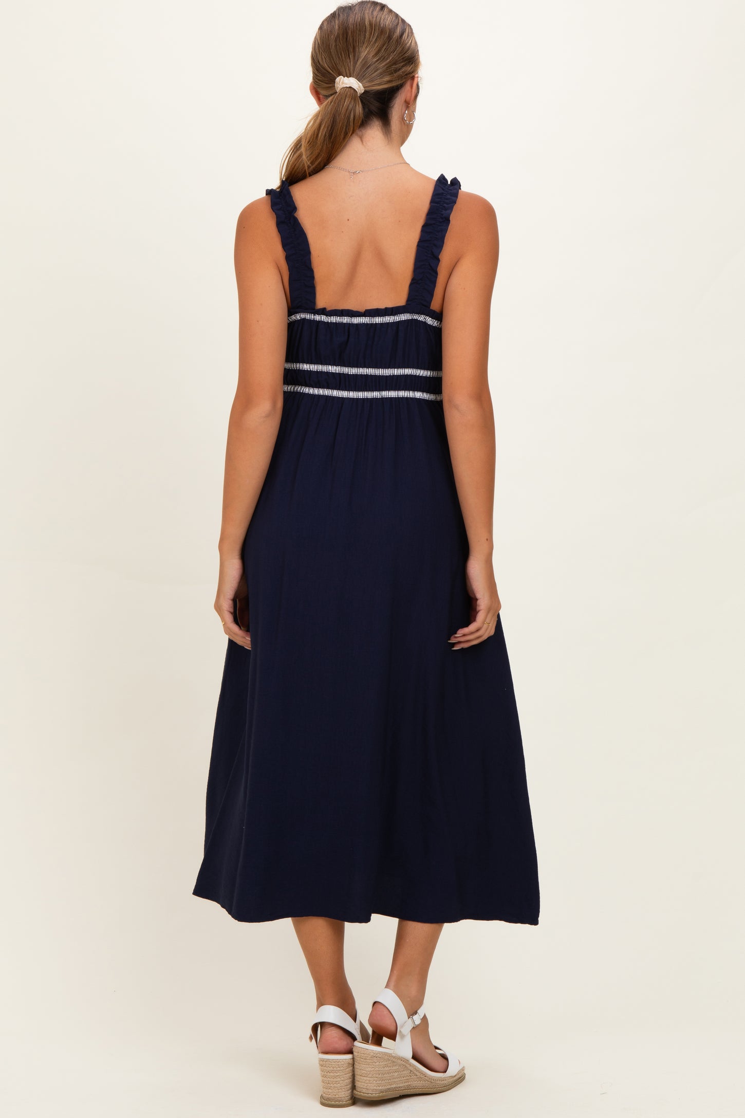 woman wearing a navy blue maternity dress with ruffled straps and back detailing, showing a relaxed fit