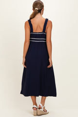 woman wearing a navy blue maternity dress with ruffled straps and back detailing, showing a relaxed fit