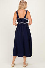 woman wearing a navy blue maxi dress with ruffled straps and smocked bodice, seen from the back