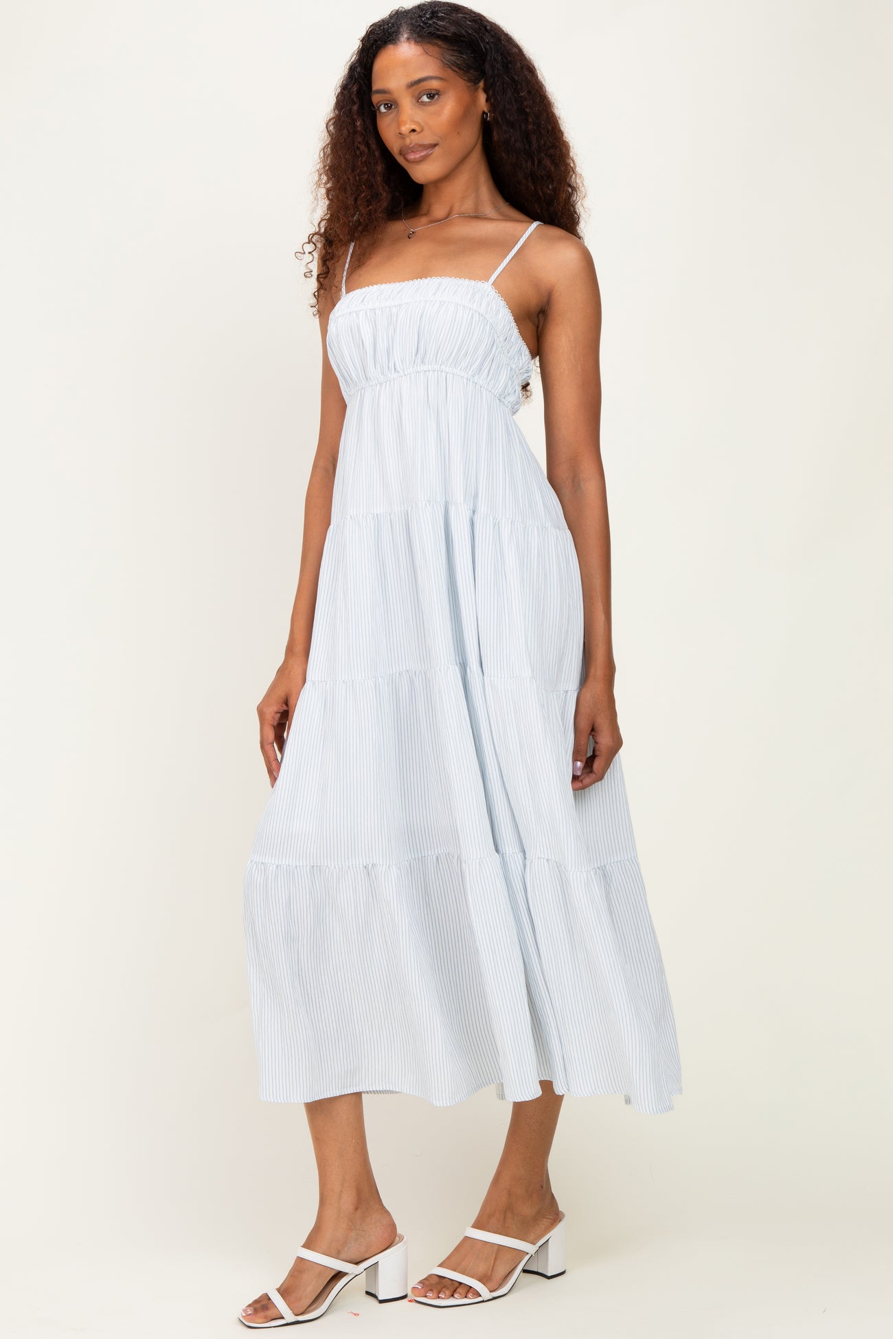 woman wearing a light blue striped tiered maxi dress with spaghetti straps