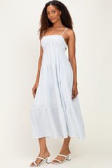 woman wearing a light blue striped tiered maxi dress with spaghetti straps