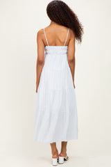 woman wearing a light blue striped tiered maxi dress with spaghetti straps, shown from the back
