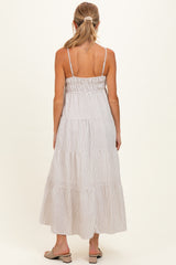 woman wearing a striped tiered maternity maxi dress, showing the back view with adjustable spaghetti straps