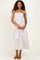 woman wearing a striped maxi dress with spaghetti straps and tiered ruffles, standing with hands in front
