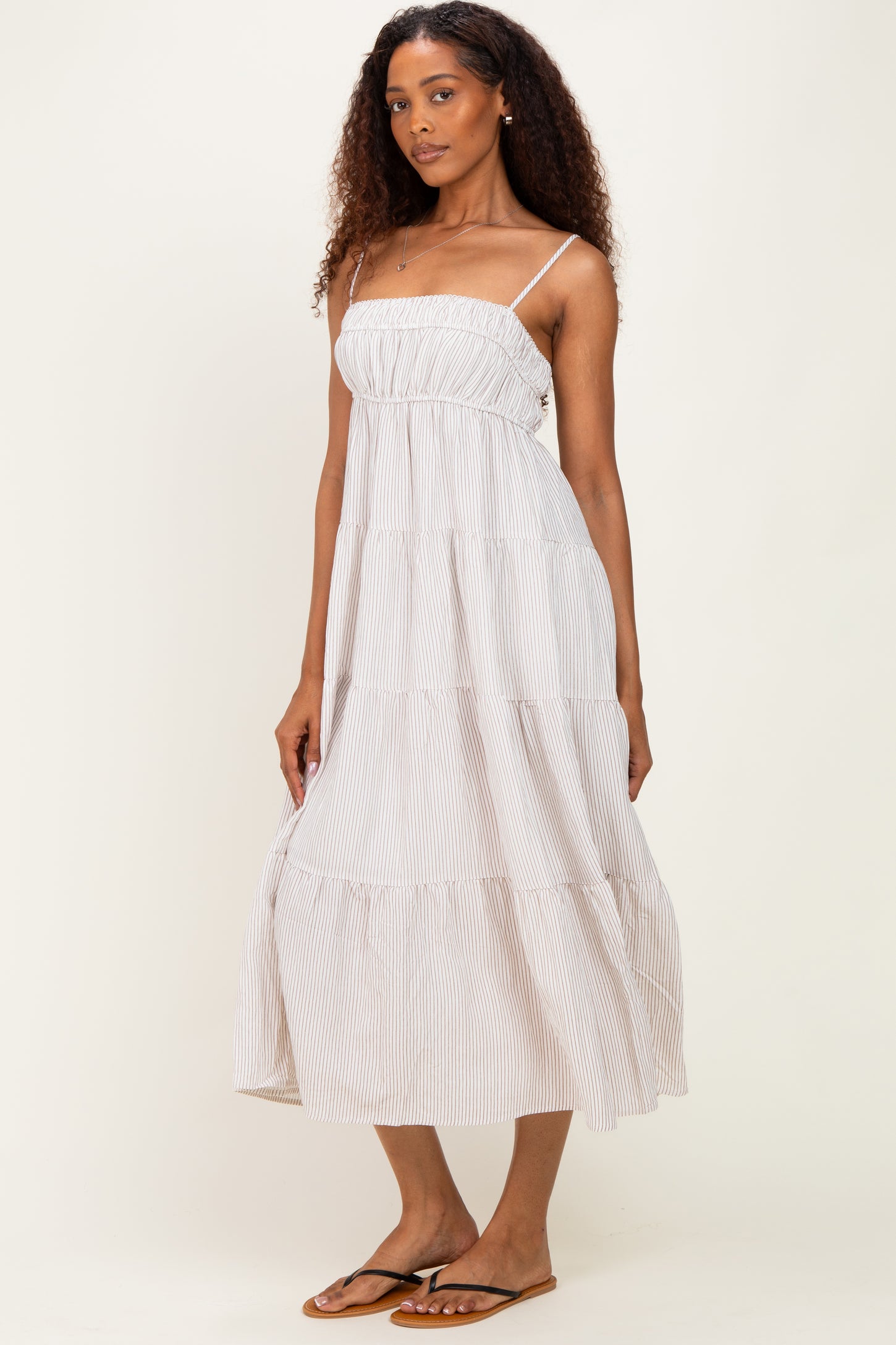 woman wearing a light striped tiered maxi dress with spaghetti straps and sandals