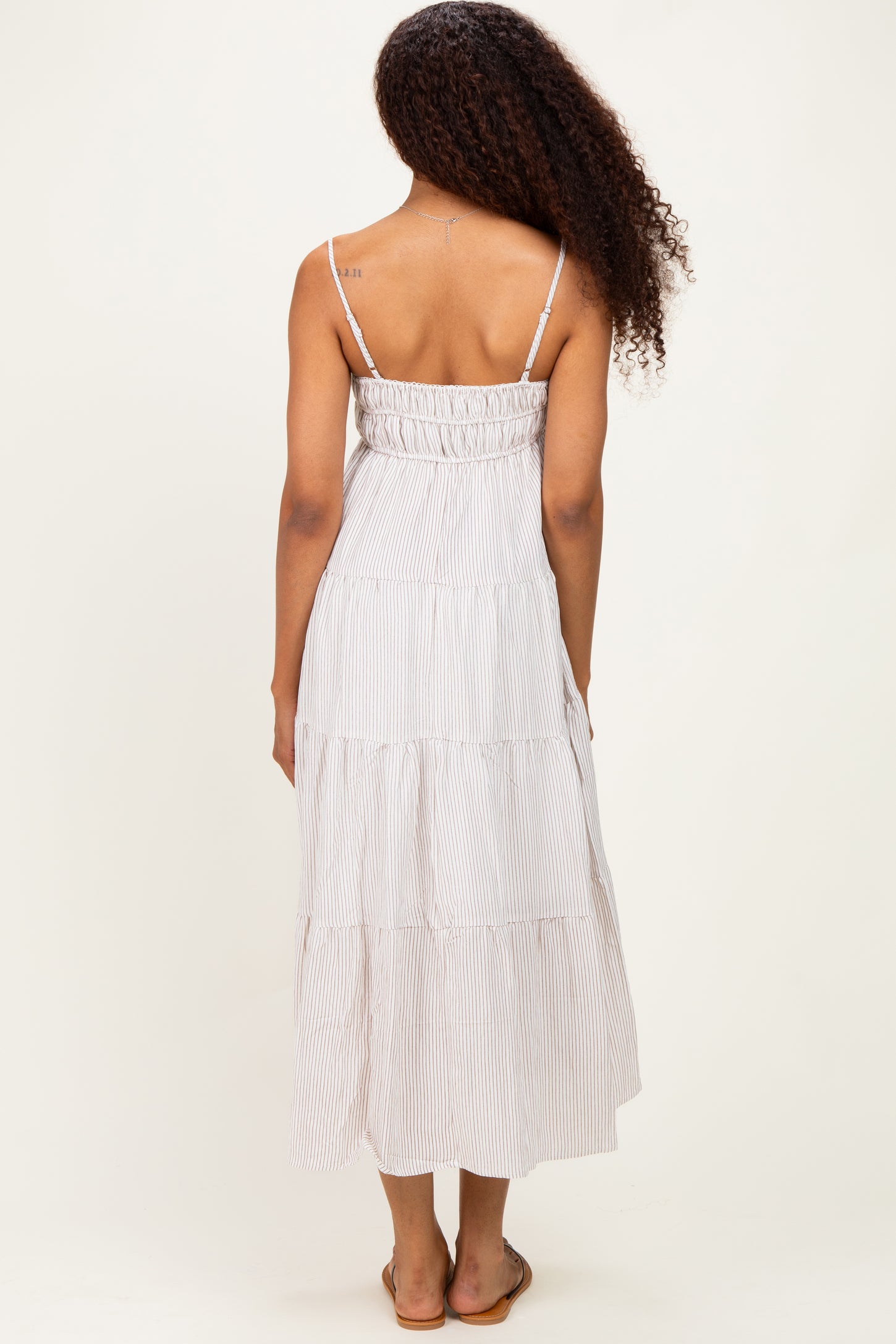 woman wearing a striped tiered maxi dress with adjustable spaghetti straps, view from the back