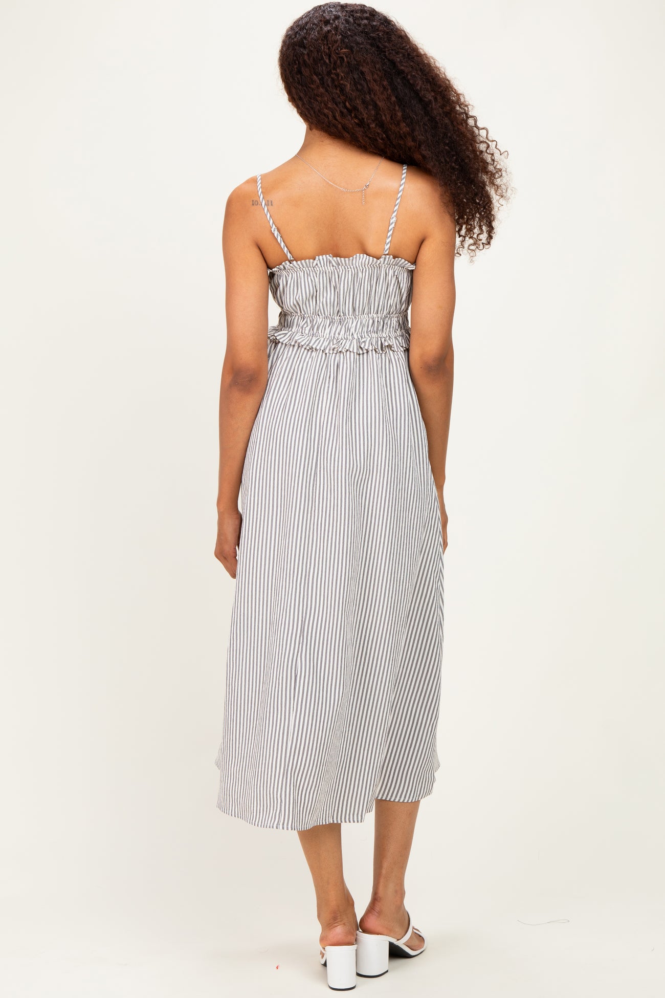 woman wearing a striped midi dress with adjustable spaghetti straps and gathered waist, view from the back