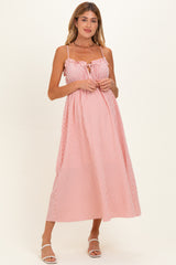 woman wearing a pink and white striped maternity dress with adjustable straps and a tie detail at the bust