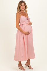 woman wearing a pink and white striped maternity dress with spaghetti straps and holding her baby bump