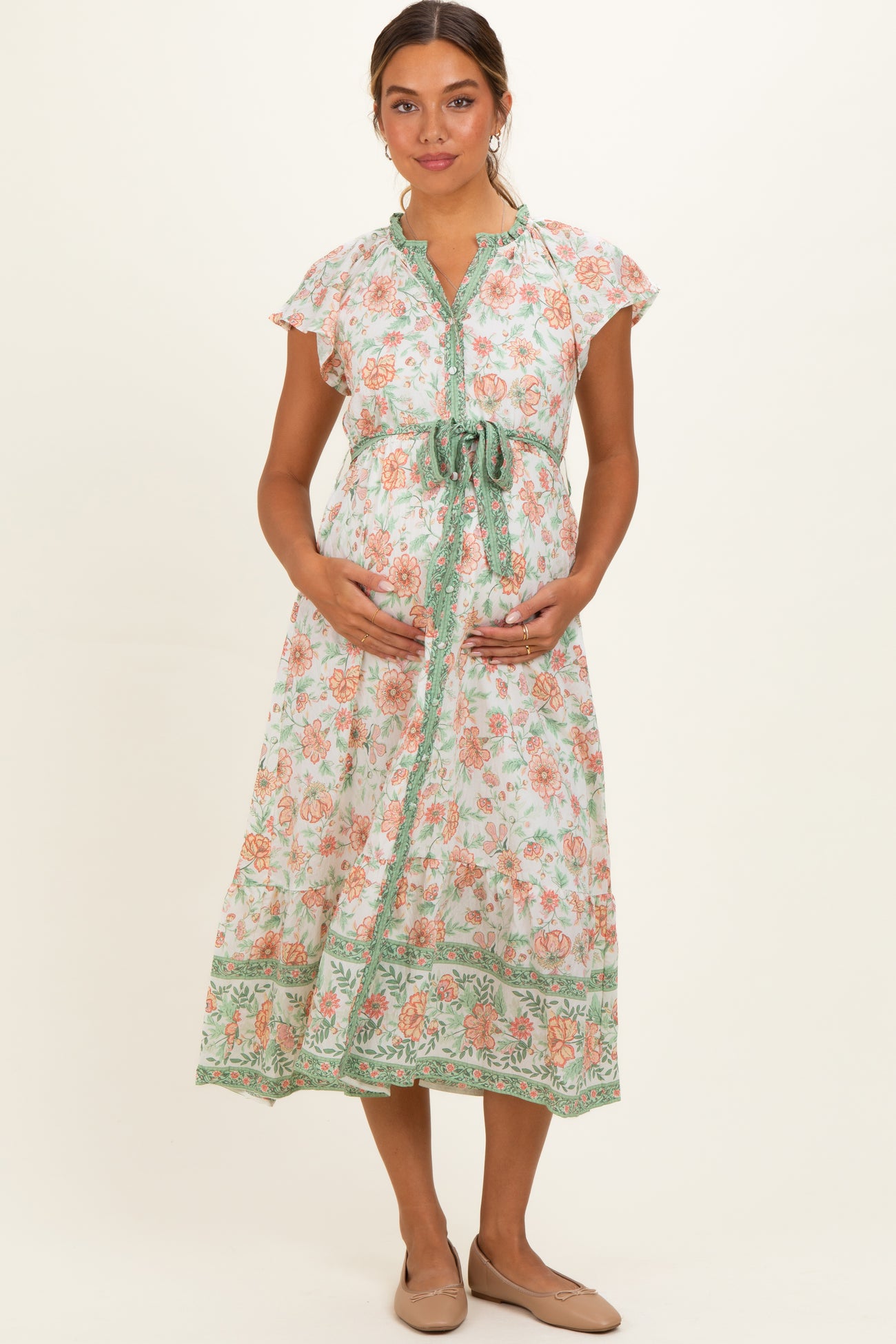 woman wearing a floral print maternity dress with a tie belt, showing her baby bump