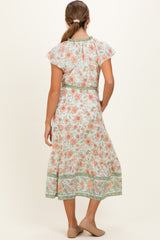 woman wearing a floral print maternity dress with short flutter sleeves and a cinched waist, showcasing a flowing skirt