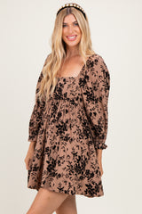 woman wearing a brown floral print mini dress with puff sleeves and a square neckline, smiling at the camera